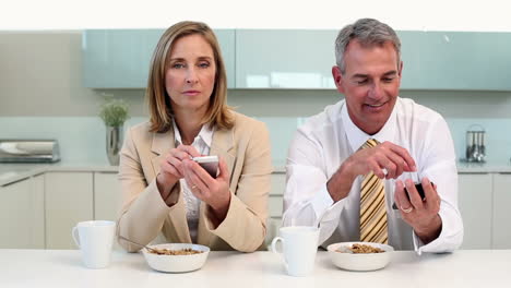 pareja desayunando y enviando mensajes de texto antes del trabajo