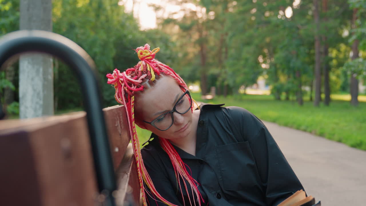 공원 배경에서 조용히 눈물을 흘리는 아티스트, 화려한 땋은 머리를 한 감성적인 시인이 야외에서 위안을 찾고, 안경을 쓴 표현력이 풍부한 시인이 자연 공원에서 친밀한 순간 동안 카타르시스를 느껴요