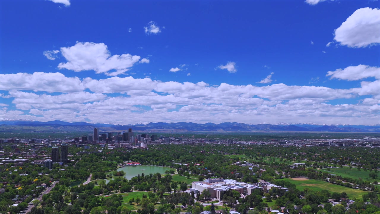 Primavera, Denver Pavilions City Park, mattina soleggiata, cielo blu, nuvole, panorama urbano del centro di Denver, Colorado, paesaggio aereo con drone, Montagne Rocciose della Front Range innevate, Lago Ferril, panoramica a sinistra