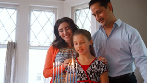 Parents-watch-daughter-light-candles-in-menorah-for-Shabbat