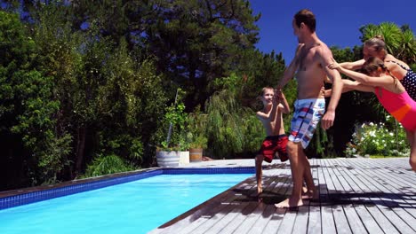 mother and kids pushing father in swimming pool