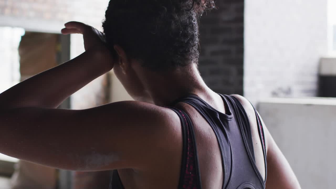 Woman wiping sweat and breathing in loft while emojis appearing from left across face after workout
