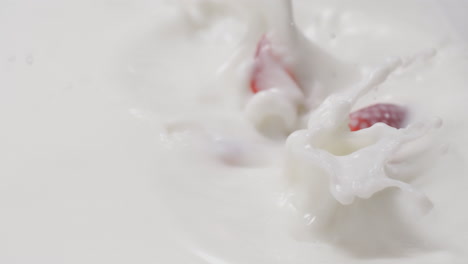 fresh strawberries falling and dipping in milk