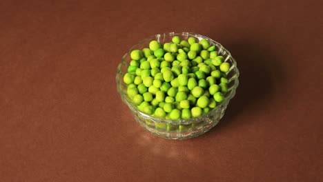 a bowl of green peas placed on a brown background