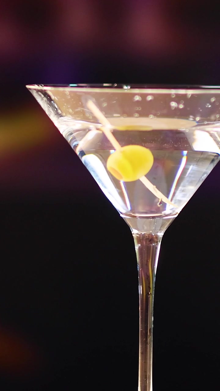 Un bicchiere da martini con una scorza di limone a spirale su uno sfondo vibrante e sfocato, creando un'atmosfera sofisticata e vivace
