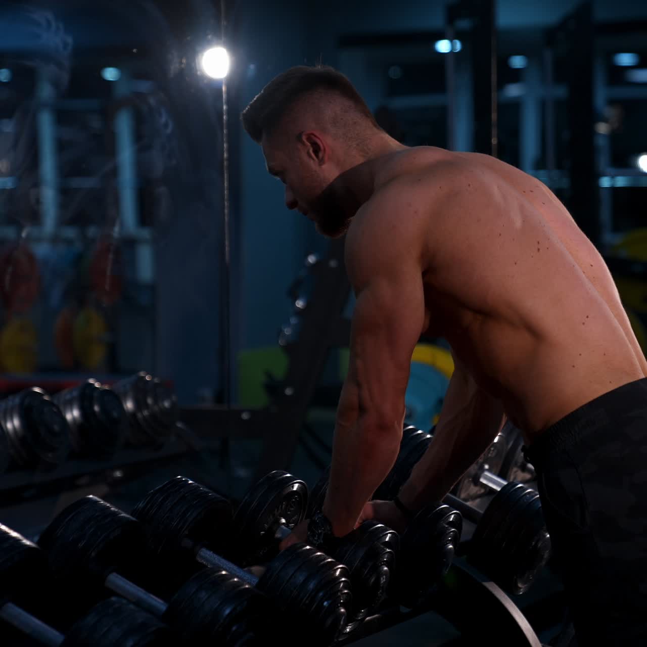 Uomo bodybuilder muscoloso che tiene manubri
