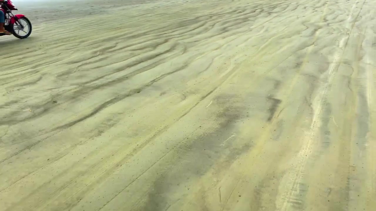 Kørsel på sandstrand med teksturerede krusninger. Høj vinkel, POV-optagelse.