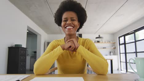 happy african american woman sitting at table making video call