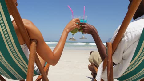 Couple-toasting-glasses-of-cocktails-at-beach-4k