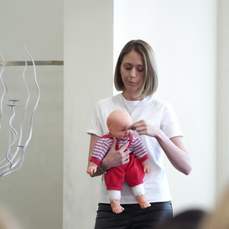 young female speaker teaching the audience. educator woman holding a doll and explaining to the listeners on the example.