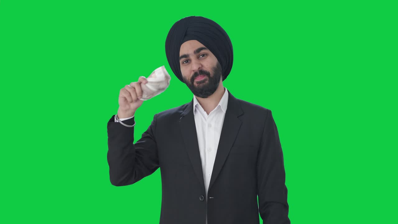 Happy Sikh Indian businessman using money as fan Green screen