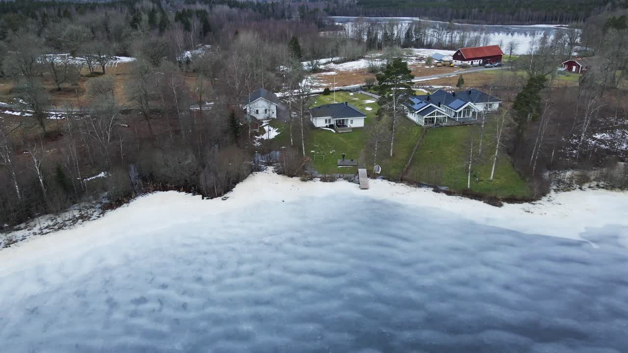 Beautiful aerial view of gorgeous homes at the edge of a frozen lake in rural Sweden