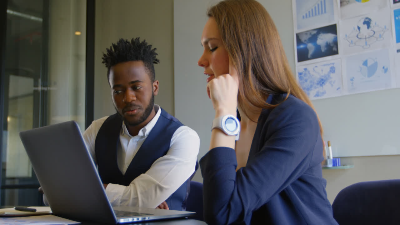 Side view of young cool mixed-race business team planning and sitting at table of modern office 4k