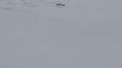 Vista-Frontal-De-La-Plataforma-Rodante-Rápida-Hacia-La-Cabaña-Cubierta-De-Nieve-En-Medio-De-La-Nada