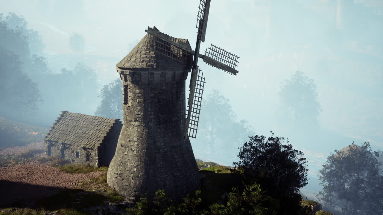 каменная ветряная мельница на вершине холма в туманном лесу