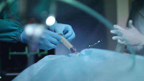 surgeon hands holding syringe with red liquid. medical operation