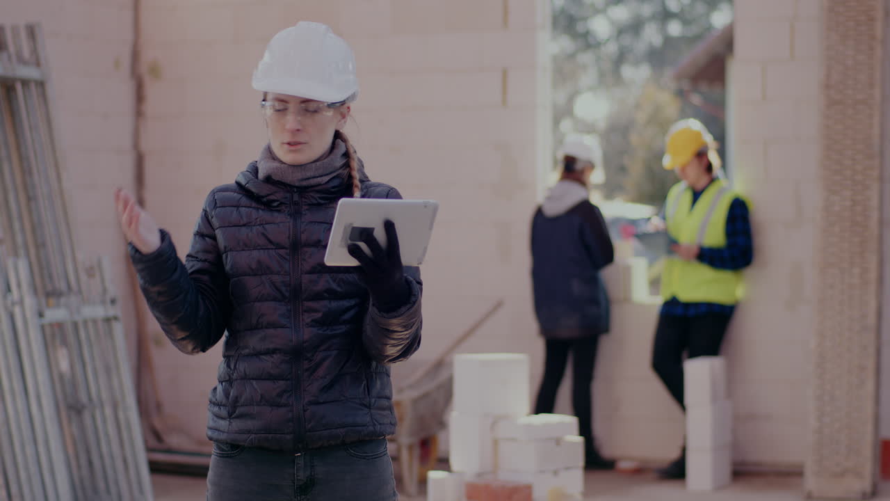 Confident young female civil engineer explaining while discussing on video call through digital tablet at construction site