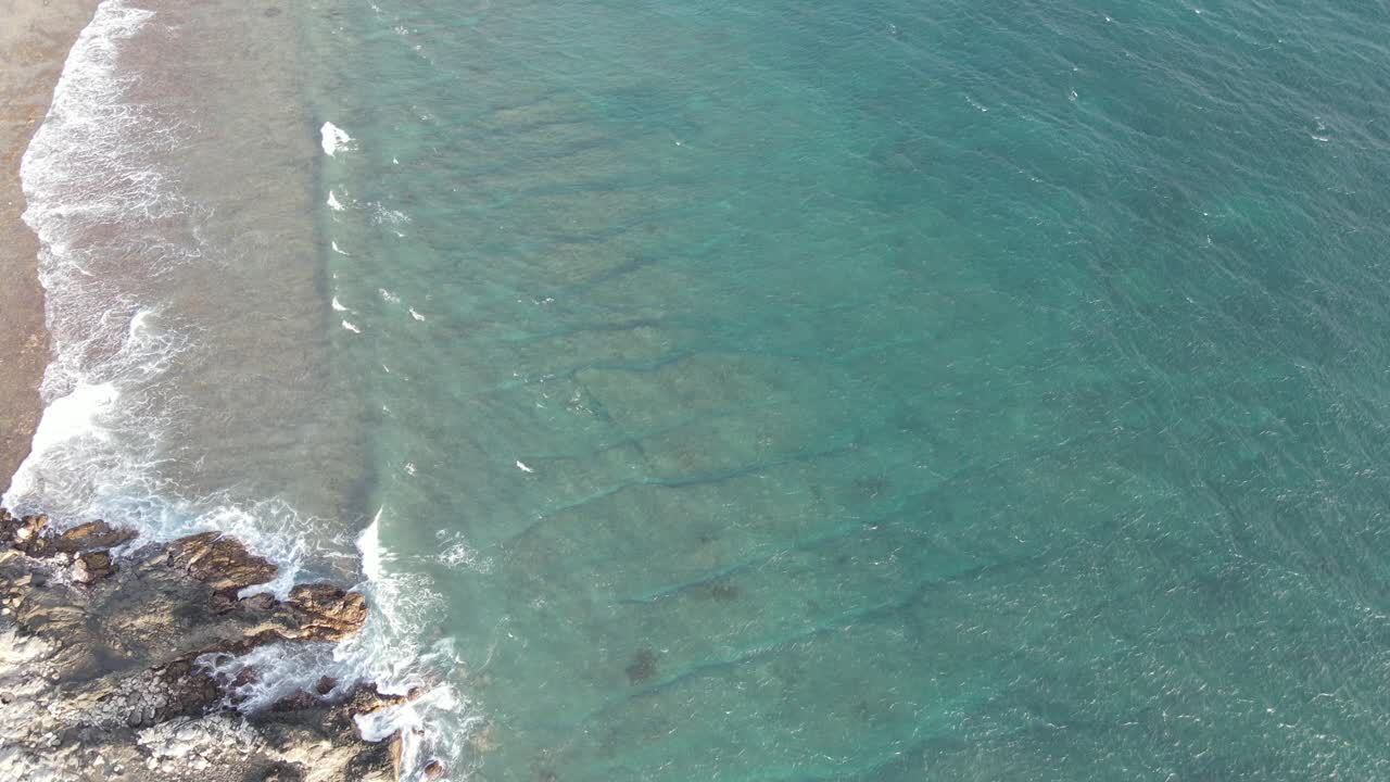 Vista aerea delle onde turchesi dell'oceano che si schiantano sulla costa rocciosa