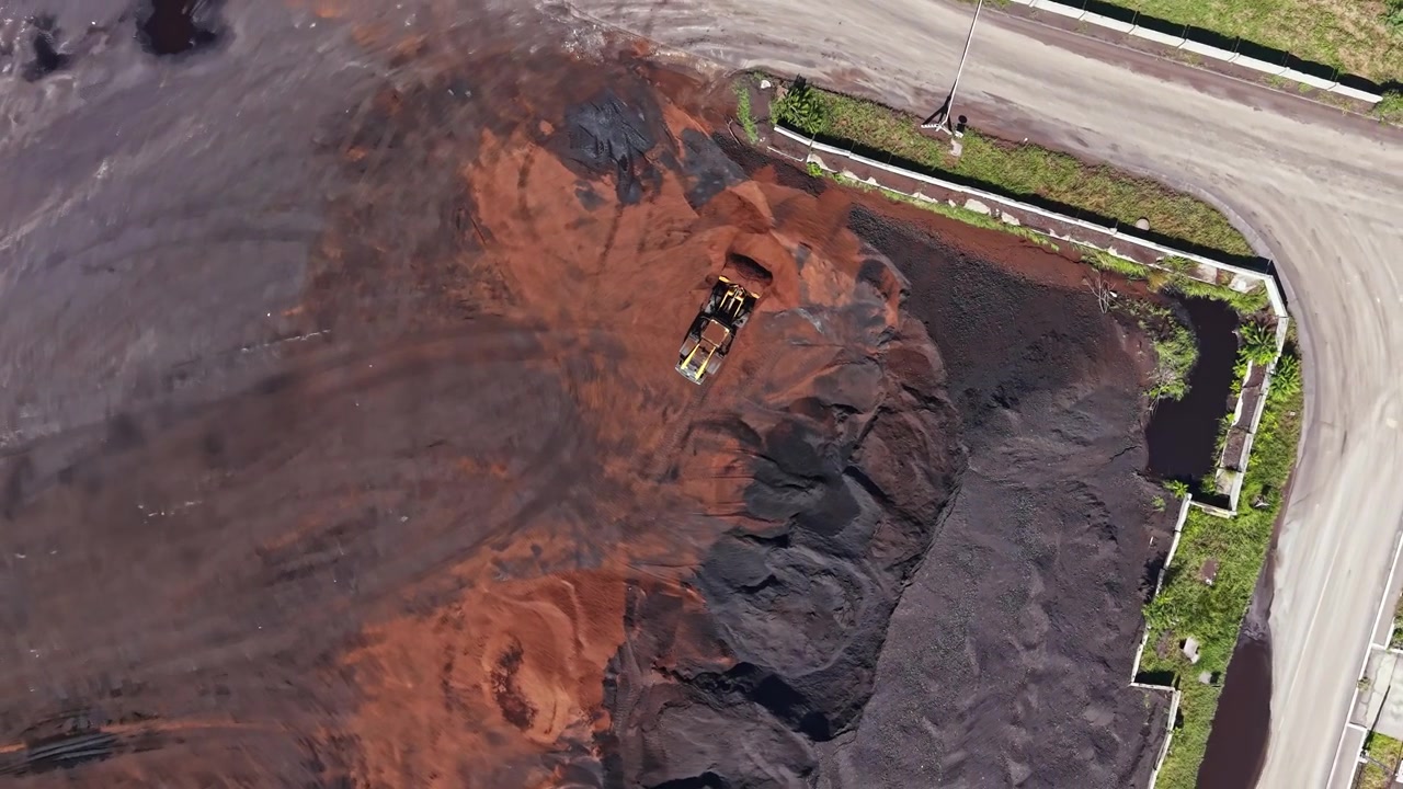 Construction site shows heavy machinery working on ground covered with materials and dirt at a busy location during daytime
