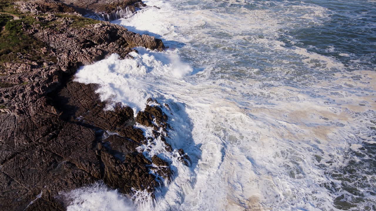 거품 같은 파도가 시버스 포인트에서 헤르마누스의 거친 바위 해안선에 부 ⁇ 히고 있습니다.