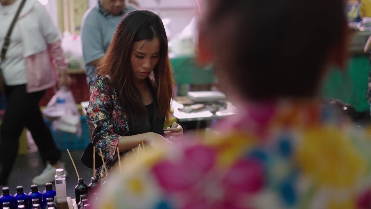 Woman testing perfume or scented products at a market stall