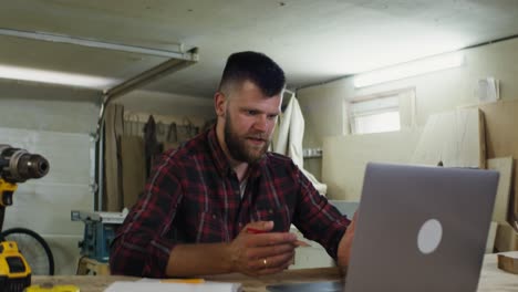 woodworker using laptop in workshop