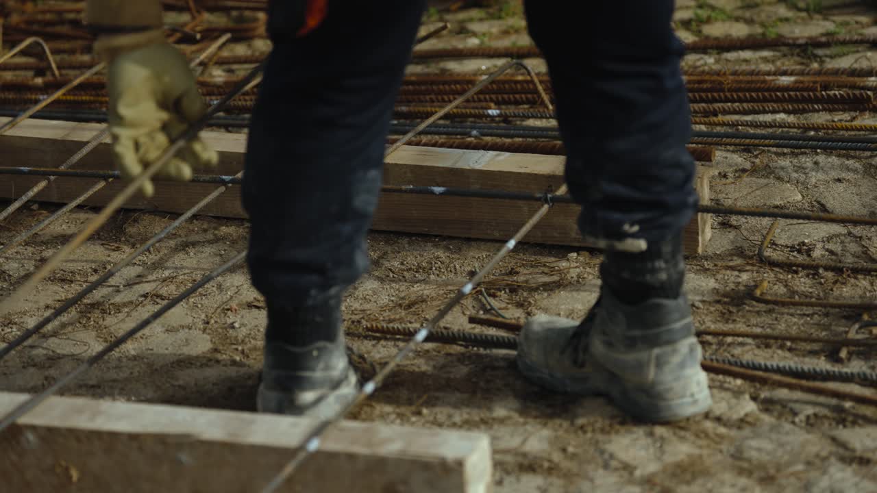 Boots stepping over steel rebar reinforcement on construction site