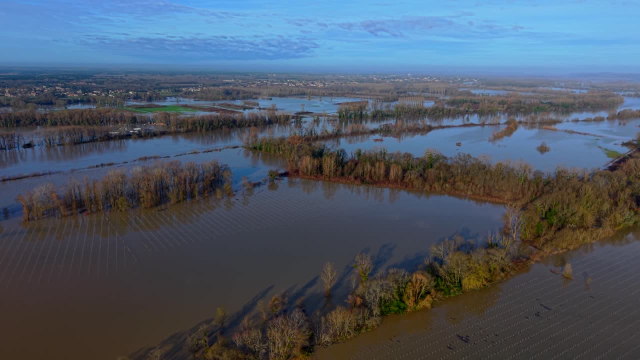 Luftfoto af oversvømmede vinmarker, der reflekterer himlen, med træer der stikker op af vandet, hvilket skaber en skarp kontrast mod det oversvømmede landskab, Rions, Frankrig.