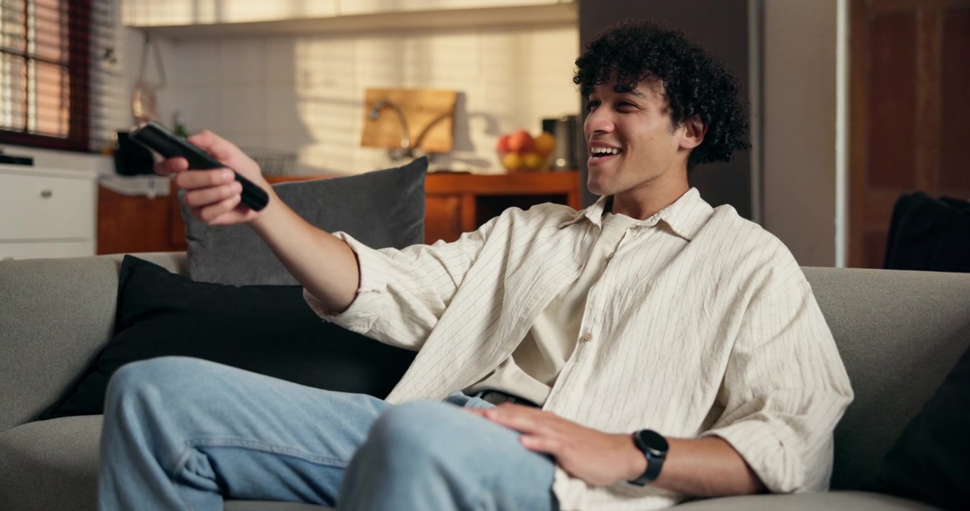 Ung mand slapper af på sofaen og ser fjernsyn derhjemme
