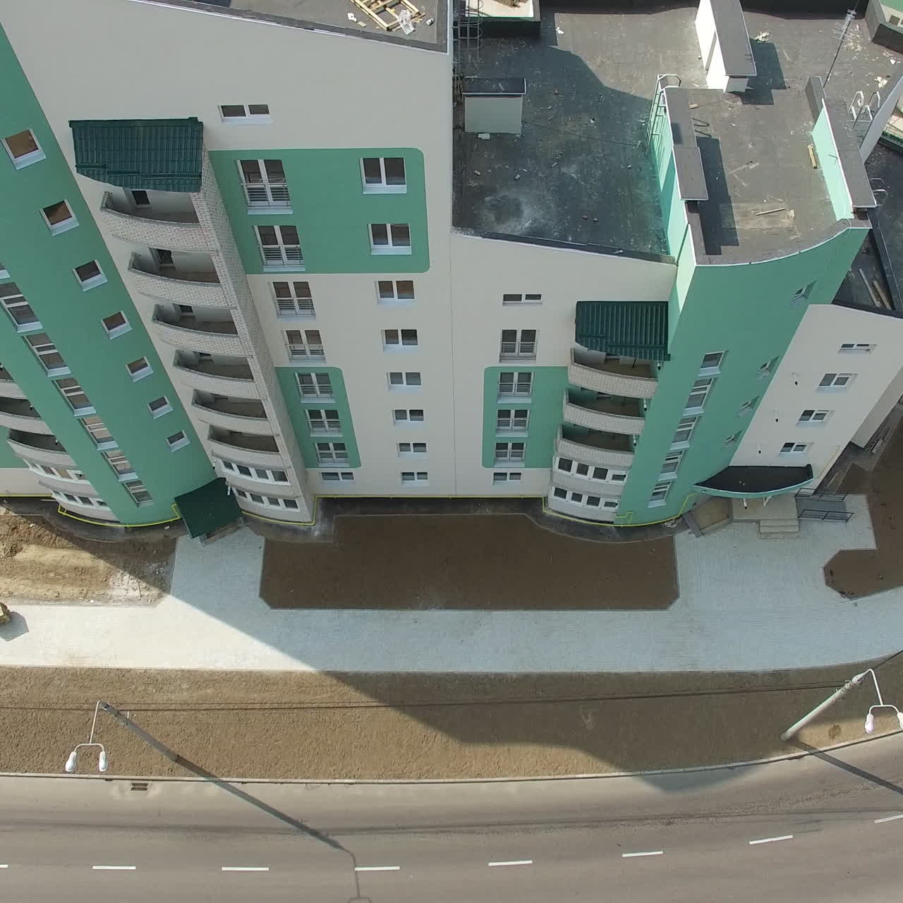 Top view of a big modern building standing close to the wide road with cars in the city. New multy-storey building. Camera moves top down