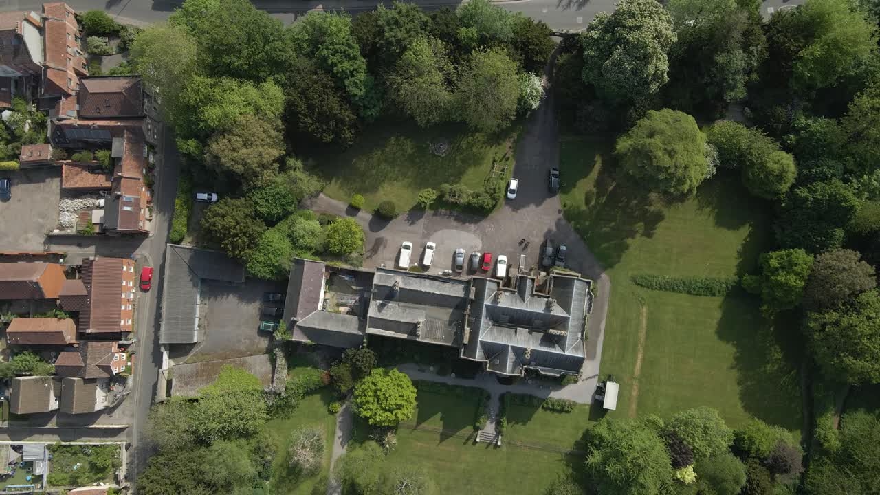 Aerial view of the Glastonbury Abbey ruins an 8th century monastery and gardens. Drone moving backwards and camera facing down over the ruins of the abbey . 4K, 60fps.