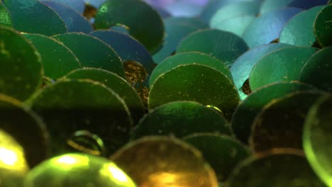 close-up view of a group of multi-colored sequins, pulling away from them as the light shines off of them