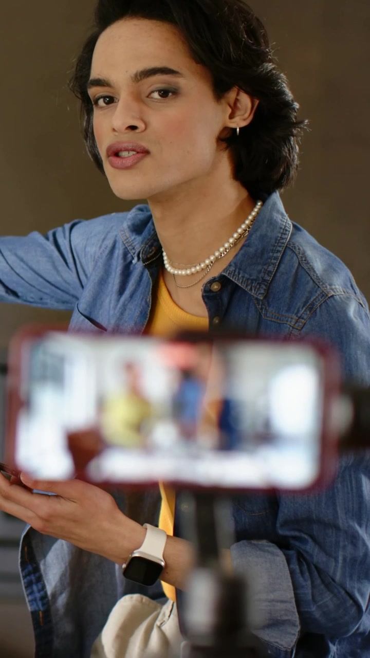 Vertical video: Phone starting recording, artist applying makeup with brush at home tutorial, denim