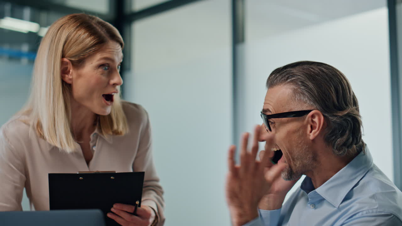 socios exitosos celebrando la victoria en la oficina. pareja emocionada dando cinco