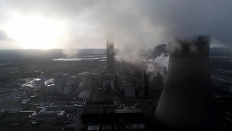 vista aérea de las torres de enfriamiento de la central eléctrica del reino unido que vuelan a través de las emisiones de vapor de humo al amanecer