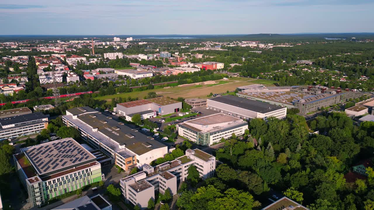 Modern film studios with offices and sound stages surrounded by trees in Berlin Adlershof, Germany. Best aerial view flight static tripod hovering drone