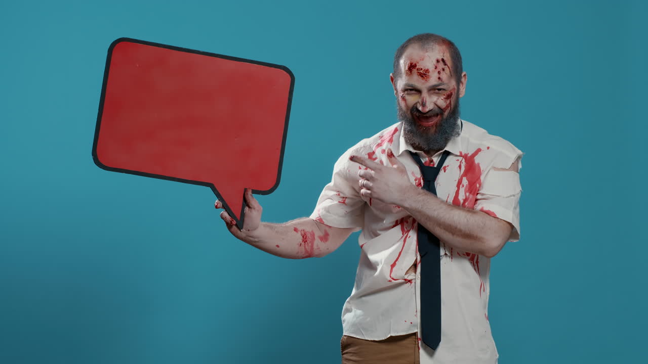 Creepy mindless zombie holding red cardboard speech bubble on blue background