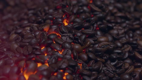 zooming in close up shot of coffee beans roasting on a orange and yellow glowing fire