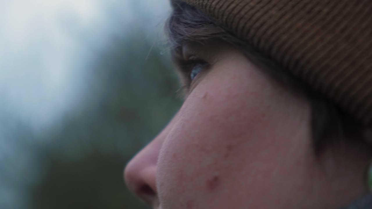 Close-up of a person looking thoughtfully into the distance, wearing a hat