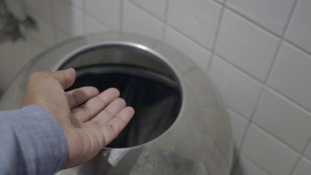Person Disposing of Tissue in a Public Restroom Trash Can