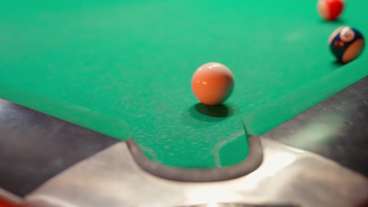 Bille de billard rayée orange tombant dans la poche d'angle