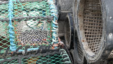 close up fishing harbour group of stacked lobster pots on coastal marine waterfront dolly right