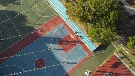 slow motion drone shot of children playing basketball at club of buenos aires in the evening