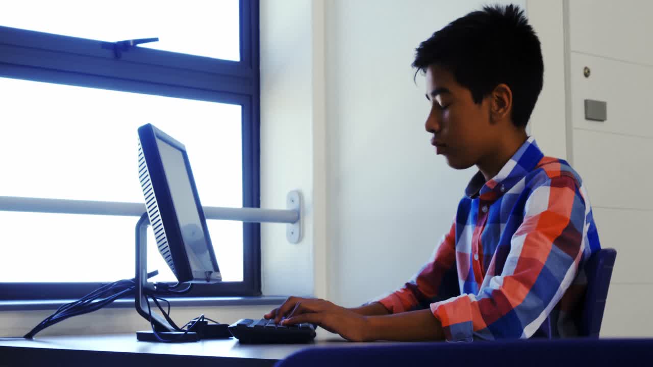 Schoolboy studying on computer in classroom