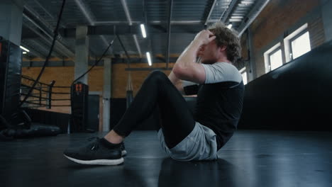 Eager-sportsman-doing-crunches-at-gym.-Fighter-warming-up-in-sport-club