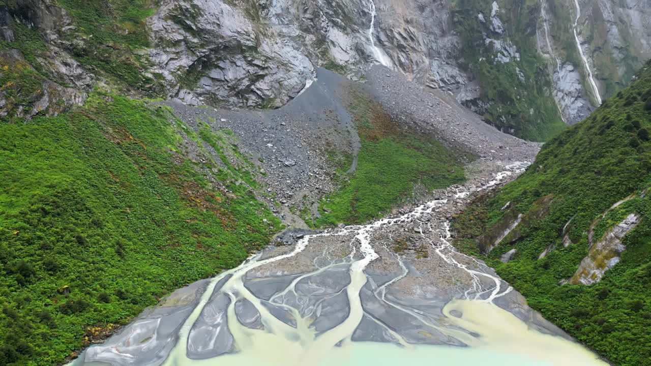 Aerial drone view of a glacier melt river with intricate channels flowing into a turquoise lake