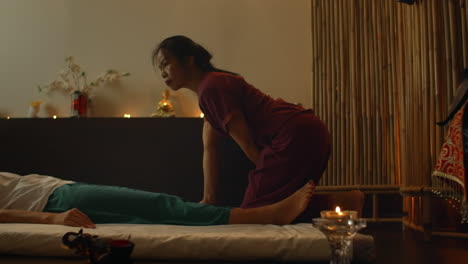 asian woman performs traditional thai massage to beautiful european woman. rehabilitation and treatment after injuries with the help of massage. relax and rest from massage of legs arms and back. therapeutic massage