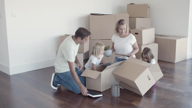 Famiglia allegra con bambini che spacchettano le cose nel nuovo appartamento.