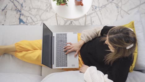 woman works alone with laptop in her modern home.