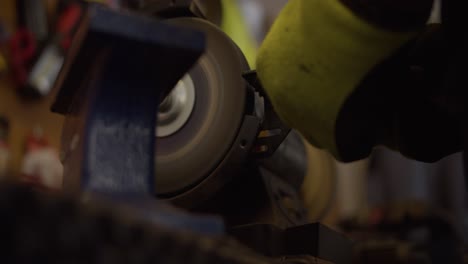 low angle shot of metal being shaped by a bench grinder, causing sparks 4k slow motion